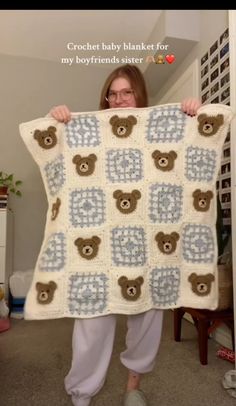 a woman holding up a crocheted teddy bear blanket