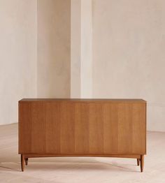 a wooden cabinet sitting on top of a hard wood floor next to a white wall