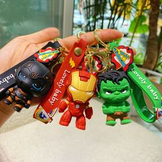 a hand holding several key chains with cartoon characters attached to them, all in different colors