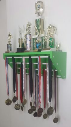 a bunch of medals are hanging on the wall next to a trophy rack with cups and spoons