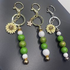 three keychains with flowers and beads on them sitting next to each other in front of a black surface