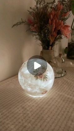 a glass bowl sitting on top of a table next to a vase filled with flowers