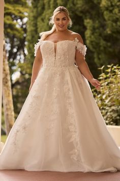 a woman in a wedding dress posing for the camera with her hands on her hips