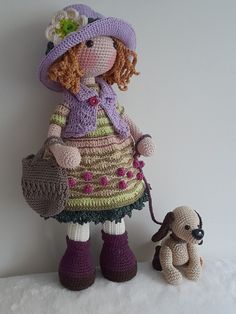 a crocheted doll with a small dog on a white surface next to it