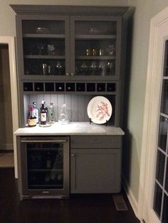 a kitchen with grey cabinets and white counter tops, wine glasses on the cabinet doors