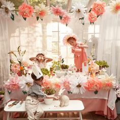 two children are sitting at a table with flowers on it and one child is playing