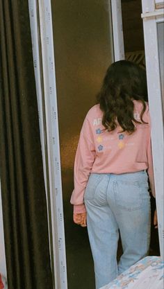 a woman standing in front of an open door with her back turned to the camera