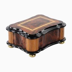 a wooden box with black and gold trimmings on the top, sitting on a white surface