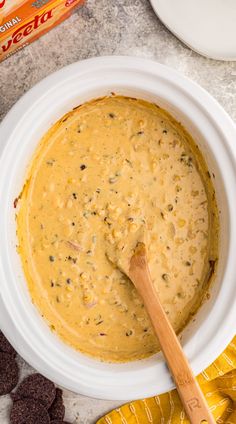 a white bowl filled with batter and chocolate chips on the side next to a wooden spoon