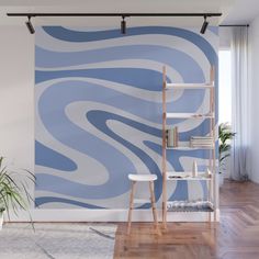 an abstract blue and white wall mural in a living room with wooden flooring, bookshelves and shelves