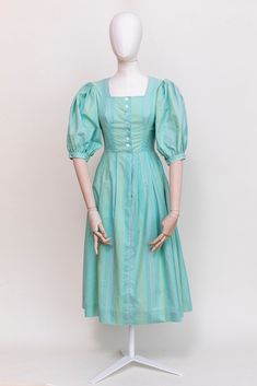 A beautiful aqua green dress with pale stripe pattern in traditional Austrian style, made of high quality cotton. Puff sleeves, square neckline, raised shoulders, buttoned from the front.  Midi length. Fabric: 100% cotton Condition: Very good vintage condition, no stains or holes. Freshly laundered and ready to wear. Measurements: Best fit: XXS-XS | EU34 | UK6 | US 4 All measurements are taken lying flat and have already been doubled Shoulders: 36cm / 14'' Sleeves: 32cm / 12,5'' Chest: 84 cm / 3 Cotton Puff Sleeve Dress With Square Neck For Daywear, Cotton Square Neck Puff Sleeve Dress For Daywear, Green Cotton Dress With Gathered Sleeves, Fitted Cotton Puff Sleeve Dress With Square Neck, Green Cotton Puff Sleeve Dress, Green Cotton Puff Sleeve Short Dress, Fitted Green Puff Sleeve Dress With Square Neck, Green Fitted Square Neck Puff Sleeve Dress, Green Fitted Cotton Puff Sleeve Dress