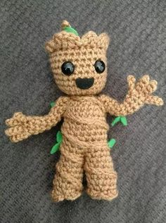 a crocheted teddy bear with green leaves on it's body and eyes