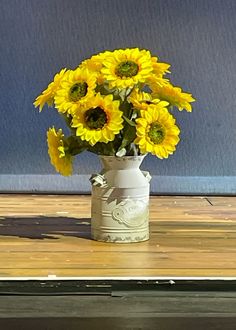 a vase filled with yellow sunflowers on top of a wooden table