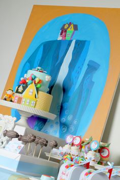 there is a cake on the table with other items in front of it and a painting behind it