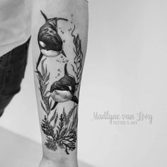 a black and white photo of a person's arm with an orca whale tattoo on it