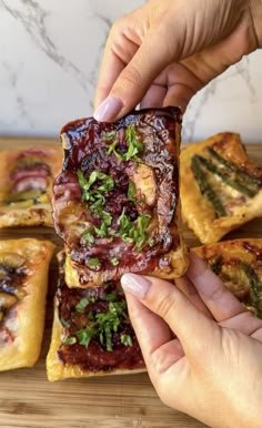 someone holding up some food on top of a wooden cutting board