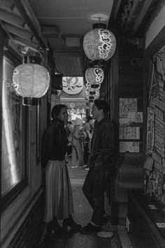 black and white photograph of two people standing next to each other in an alleyway