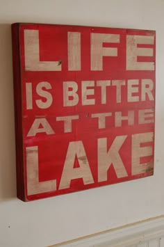 a red and white sign that says life is better at the lake hanging on a wall