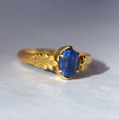 A beautiful Natural Ceylon Sapphire ring. The buttery yellow hand-made mounting tests to 22k in gold fineness. The cathedral-style mounting has a tapered style shank measuring 3.3 mm in width tapering to 2.4 mm at the base of the shank. Prong set into the ring is an oval-shaped and faceted natural blue sapphire measuring 7.47 x 5.00 mm. The sapphire has medium Ceylon blue body color and is of A quality. Both sides of the ring have fleur-de-lis style design work. The ring mounting weighs 3.2 dwt with stone. The setting is closed back. This piece exhibits usual wear associated with age, please see the detailed photos included with this listing for a full account of the condition.  This item is sold as-is, no returns.  Please ask any questions prior to purchase.  Thank you for looking!   US s Gold Oval Yellow Sapphire Ring, Oval Yellow Sapphire Ring In Gold, Gold Sapphire Ring With Gemstone, Formal Gold Ring With Yellow Sapphire, Formal Gold Sapphire Ring With Yellow Sapphire, Heirloom Yellow Gold Rings With Yellow Sapphire, Heirloom Yellow Gold Ring With Yellow Sapphire, Heirloom Yellow Sapphire Ring In Yellow Gold, Gold Sapphire Rings Hand Forged