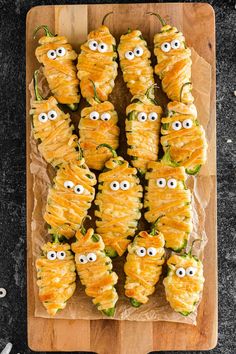 a wooden cutting board topped with cheesy pastries covered in googly eyes