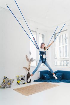 a woman is jumping in the air with her arms and legs stretched out while holding onto some wires