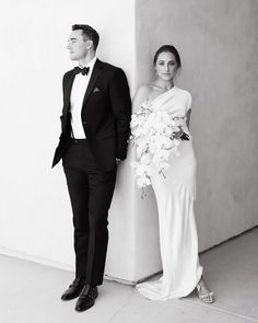 a man in a tuxedo standing next to a woman in a white dress