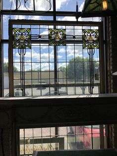 a window with stained glass in the middle and cars parked on the street behind it