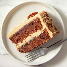 a piece of carrot cake on a plate with a fork and knife next to it