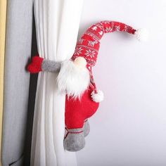 a red and white santa clause hat hanging on the side of a curtain