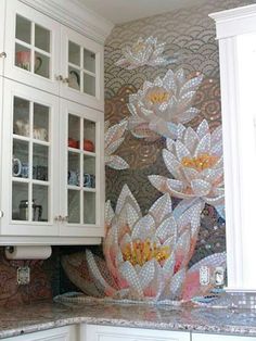 a kitchen with white cabinets and flowers painted on the backsplash wall behind it