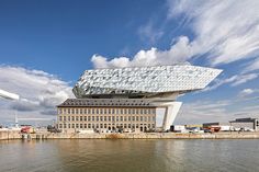 a large building sitting next to a body of water with clouds in the sky above it