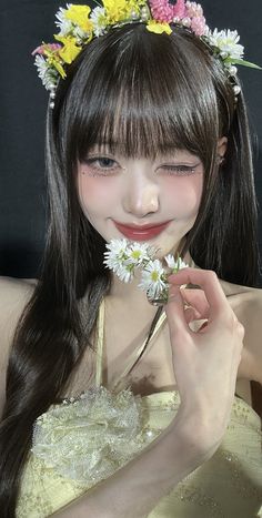 a girl with long hair wearing a flower crown and holding daisies in her hand