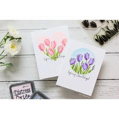 three cards with flowers on them sitting next to a stamper and some other items