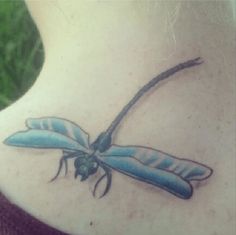 a blue dragonfly tattoo on the back of a woman's neck