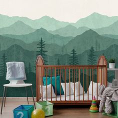 a baby's room with mountains and trees painted on the wall, including a crib