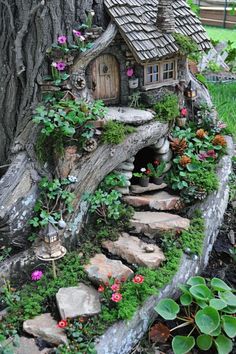 a fairy house built into the side of a tree trunk with flowers growing out of it