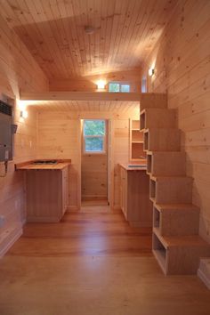 the interior of a tiny cabin with wood floors and walls, built in shelving units