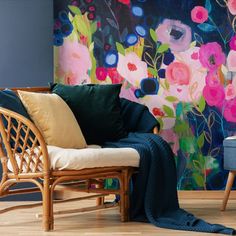 a chair with a blanket on it in front of a floral wall mural