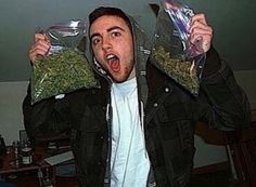 a man holding two bags of food in front of his face while standing next to a desk