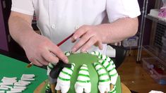 someone is decorating a green and white cake