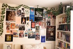 a bedroom with bookshelves, plants and pictures on the wall above it's bed