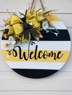 a welcome sign hanging on the side of a white wooden wall with yellow and black stripes