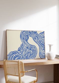 a blue and white painting sitting on top of a wooden desk next to a chair