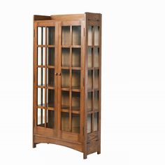 a wooden bookcase with glass doors on the top and bottom shelves, in front of a white background