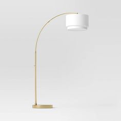 a floor lamp with a white shade on it's side and a gold base