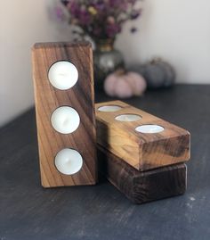 two wooden candlesticks sitting on top of a table next to a vase with flowers