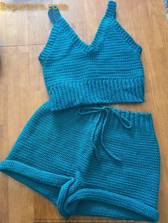 two pieces of blue knitted clothing sitting on top of a wooden floor