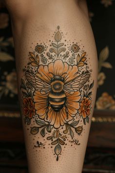 a woman's leg with a tattoo on it that has a bee and flowers