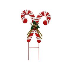 a red and white candy cane on top of a metal stand with bowknots