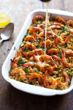 a pan filled with shrimp and rice being drizzled with sauce